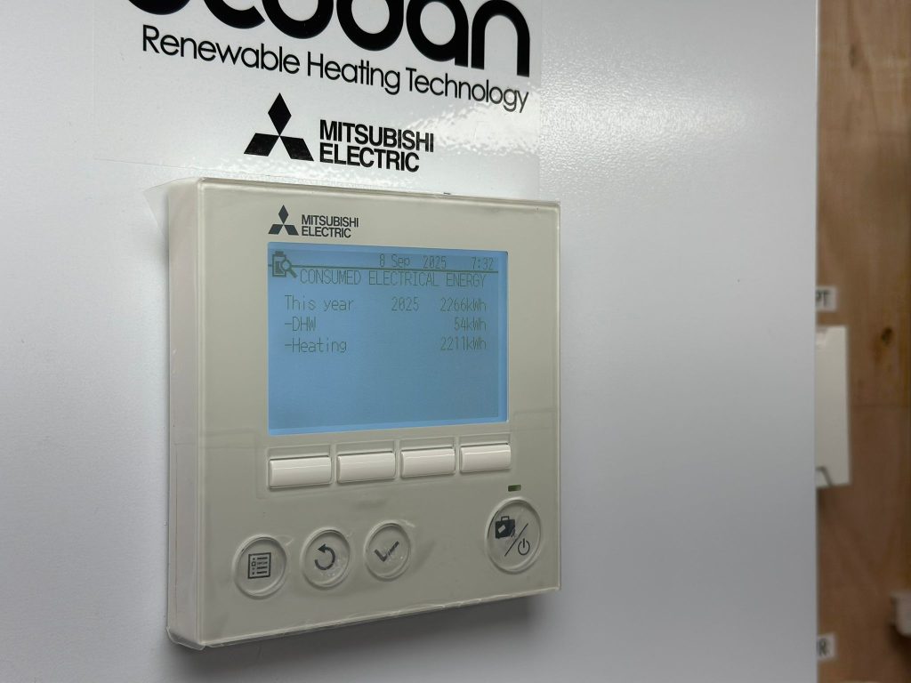 Mitsubishi Electric heat pump controller showing monthly and yearly electricity consumption data.